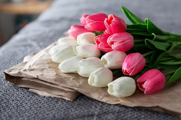 Photo bouquet frais de tulipes blanches et roses sur du papier recyclé sur fond gris