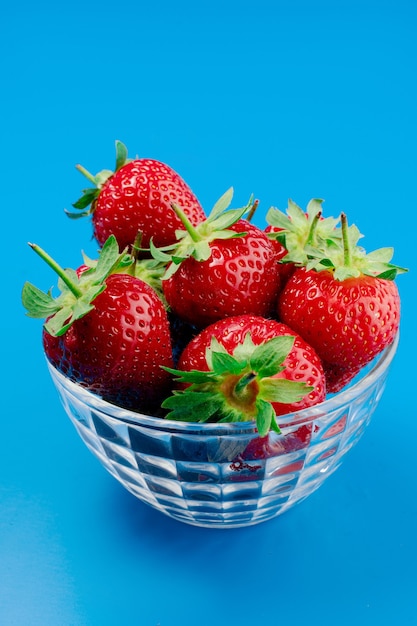 Bouquet de fraises dans un bol sur mur bleu