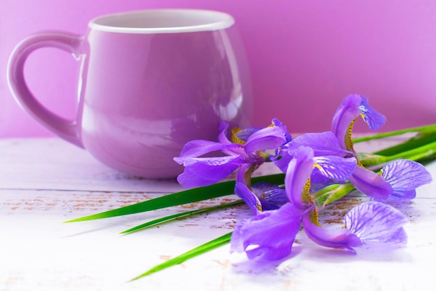 Un bouquet d'iris bleus et de tasse lilas sur la table sur fond violet