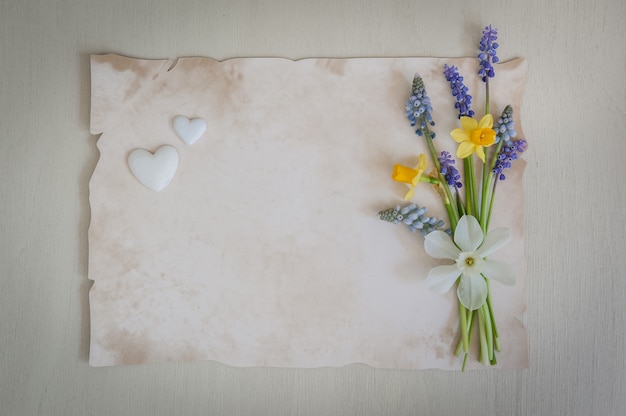 Bouquet de jonquilles et de fleurs muscari sur un fond en bois avec des coeurs.