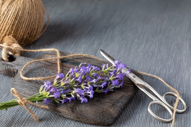 Bouquet de lavande sur planche de bois, corde de jute et ciseaux sur fond gris. Concept de jardinage, aromathérapie