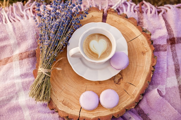 Un bouquet de lavande violette, une tasse blanche avec du café, des biscuits et un plaid à la ferme