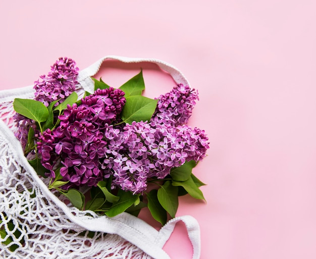 Bouquet de lilas dans un sac en filet écologique shopping réutilisable sur surface rose