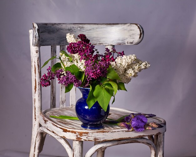 Bouquet de lilas dans un vase sur une chaise en bois Vintage