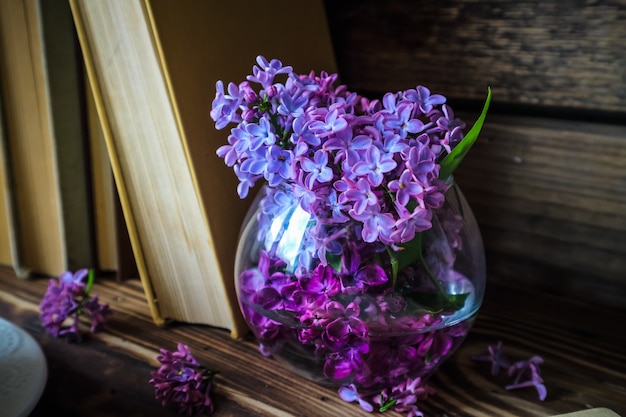 bouquet de lilas et une tasse de thé blanc sur un fond en bois