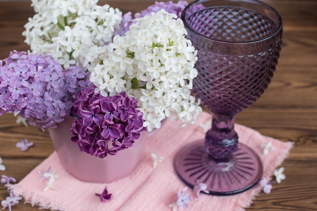 Un bouquet de lilas avec un verre à vin Le concept de style rustique