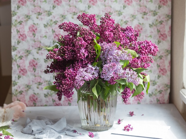 Bouquet de lilas violet dans un vase. Nature morte aux branches fleuries de lilas dans des vases. Photo de style libre.