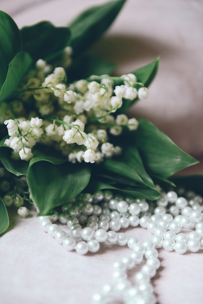 Photo bouquet de lys de la vallée à l'intérieur et perles de perle