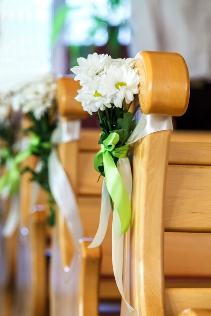 Un bouquet de marguerites blanches est attaché au dossier d&#39;une chaise