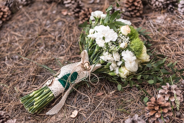 Bouquet de mariage au sol sur la litière d'épinette autour des cônes