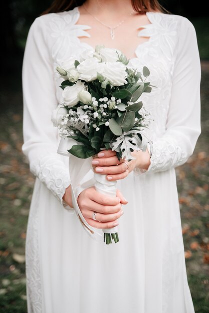 Bouquet de mariage de beauté de fleurs roses et de branches d'eucalyptus dans les mains de la mariée.