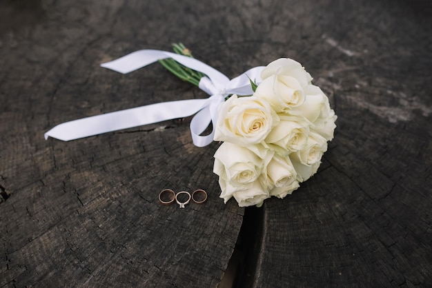 Bouquet de mariage Décor de mariage Anneaux de mariage et bouquet de mariage de roses blanches sur le fond en bois