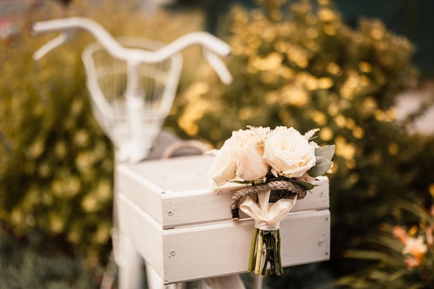 Bouquet de mariage à l'extérieur de la mariée dans une robe beige tient le bouquet de fleurs de mariage de fleurs et de verdure