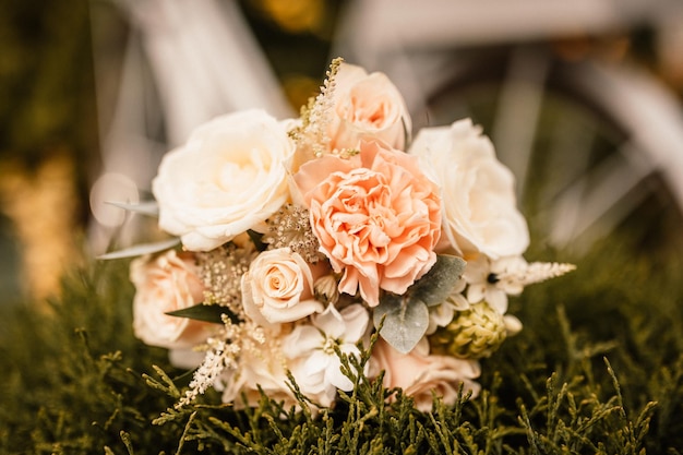 Bouquet de mariage à l'extérieur de la mariée dans une robe beige tient le bouquet de fleurs de mariage de fleurs et de verdure