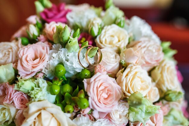 Bouquet de mariage lumineux de roses roses blanches d'été avec des anneaux de mariage