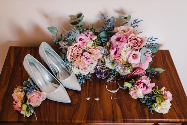 Bouquet de mariage de la mariée de fleurs roses roses et verts élégantes chaussures classiques élégantes et deux boucles d'oreilles de mariage en argent bracelet parfum Gros plan Vue de dessus