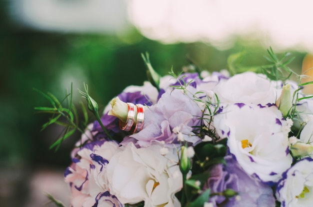 Bouquet de mariée avec des anneaux d'or sur l'herbe