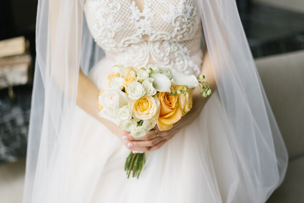 Bouquet de mariée blanc et orange dans les mains de la mariée