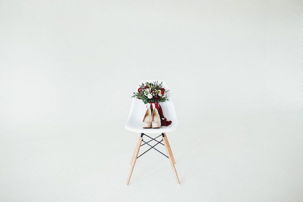 Bouquet de mariée sur la chaise en bois blanche avec mur blanc.