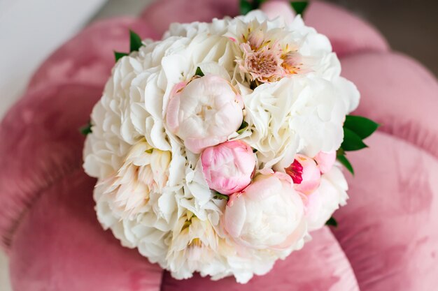 Photo bouquet de mariée chic avec une pivoine allongée sur un fauteuil rose tendre