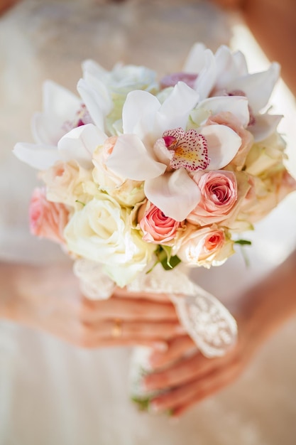 Bouquet de mariée dans les mains de la mariée avec des orchidées et des roses