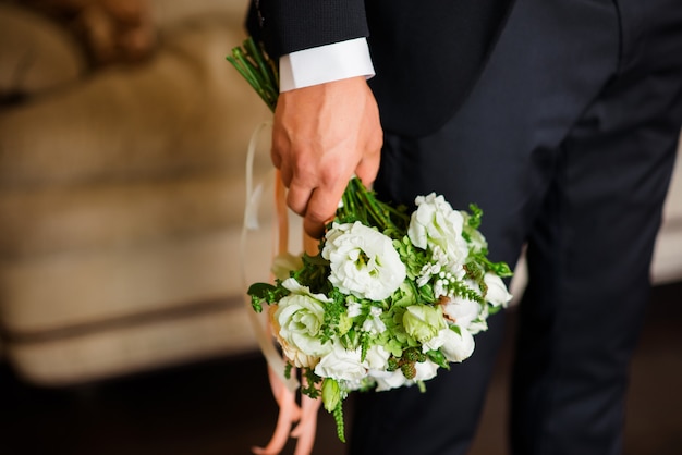 Bouquet de mariée entre les mains du marié.