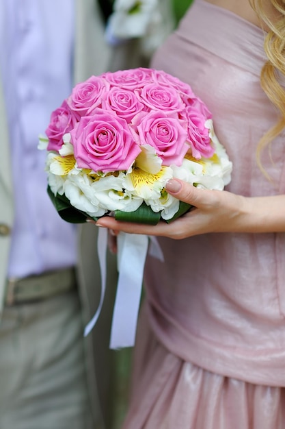 Bouquet de mariée de fleurs roses et blanches dans les mains de la mariée