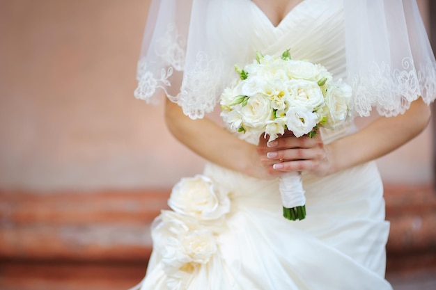 Bouquet de mariée de fleurs de roses blanches dans les mains de la mariée