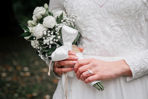 Bouquet de mariée de fleurs roses et de branches d'eucalyptus dans les mains de la mariée