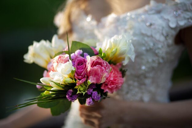 Bouquet de mariée avec des fleurs roses dans les mains de la mariée