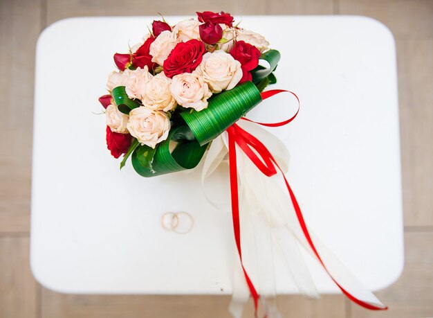 Bouquet de mariée avec des fleurs rouges et blanches sur une chaise avec un anneau