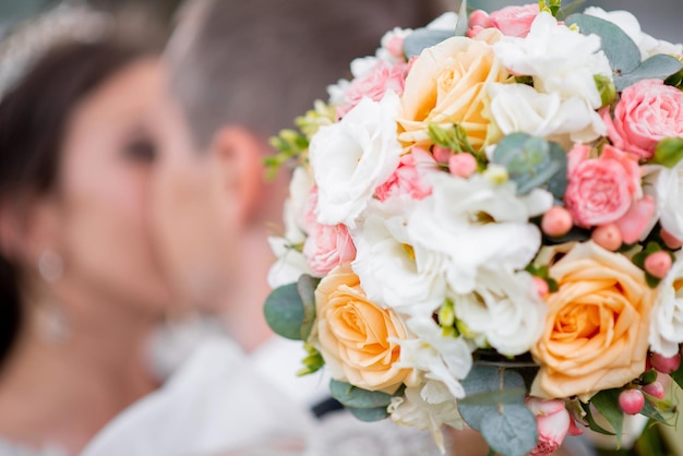 Bouquet de mariée grand entre les mains des mariés dercore de roses blanches et roses xA