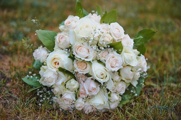 Bouquet de mariée mariage de roses crème avec gypsophile forme ronde sur un fond d'herbe