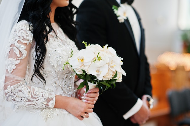 Bouquet de mariée d'orchidées blanches sur la main de la mariée à la cérémonie de l'église