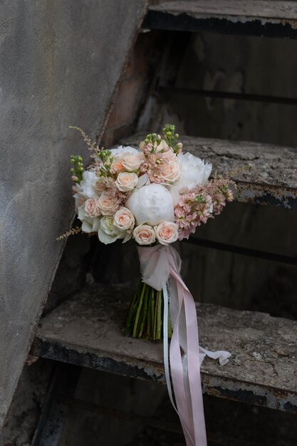 Bouquet de mariée pêche et blanc sur fond de pierre sombre composé de roses pivoines et d'astilbe Jour du mariage