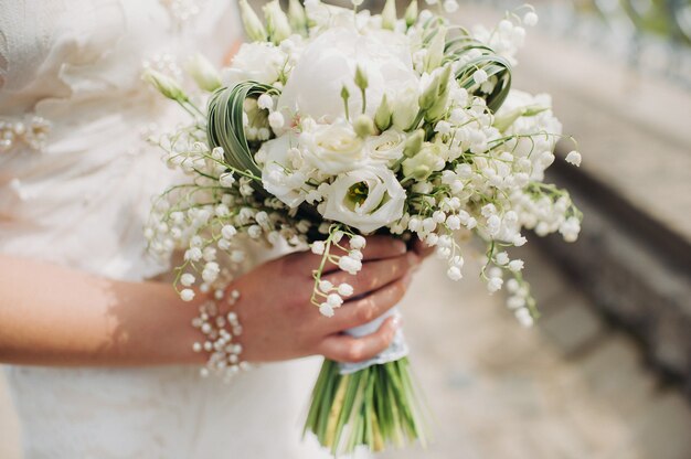 Bouquet de mariée avec des pivoines dans les mains de la mariée sous le voile