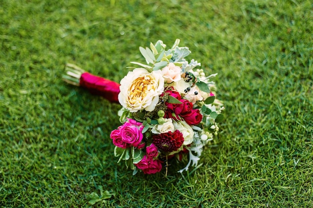 Bouquet de mariée de roses allongé sur la pelouse