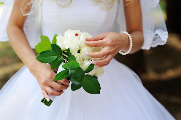 Bouquet de mariée de roses blanches dans les mains de la mariée