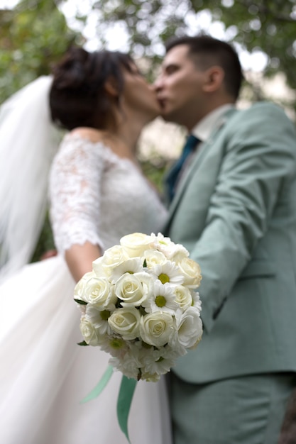 Bouquet de mariée de roses blanches sur le fond des baisers de jeunes mariés