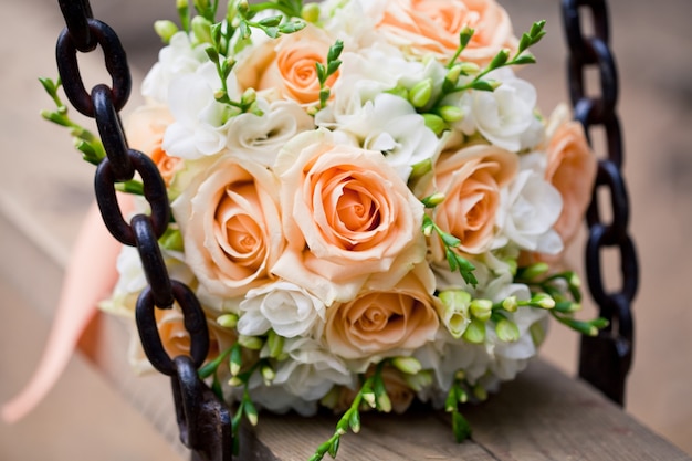 Photo bouquet de mariée avec des roses et des branches vertes sur la balançoire