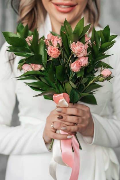 Bouquet de mariée avec des roses roses dans les mains de la mariée