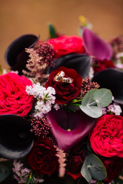 Bouquet de mariée rouge. anneaux de mariée dans le parc.