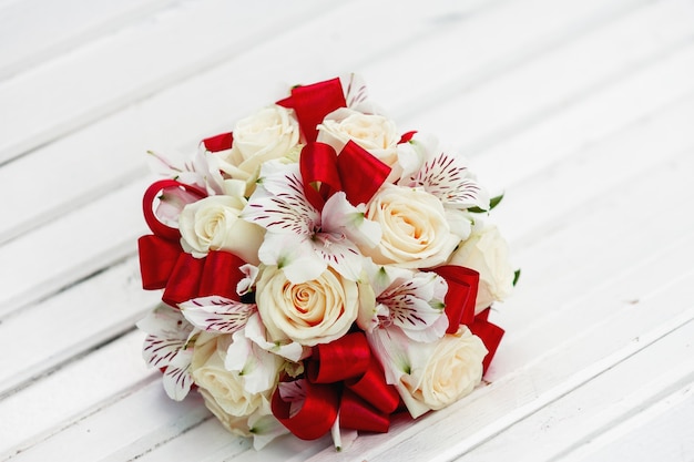 Bouquet de mariée avec rubans rouges, roses beiges et orchidées