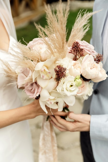 Le bouquet de la mariée se tient à côté d'autres accessoires de mariage sur un beau bouquet élégant de fond avec des fleurs séchées
