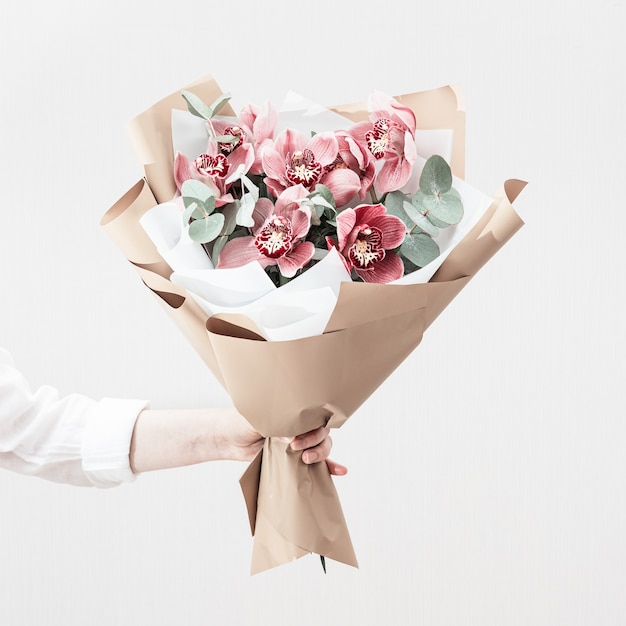 Bouquet à la mode avec des orchidées rouges dans les mains de la femme. Belles fleurs en cadeau