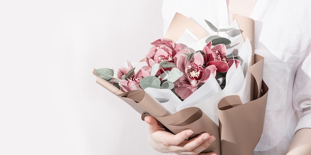 Bouquet à la mode avec des orchidées rouges dans les mains de la femme Belles fleurs comme cadeau d'anniversaire