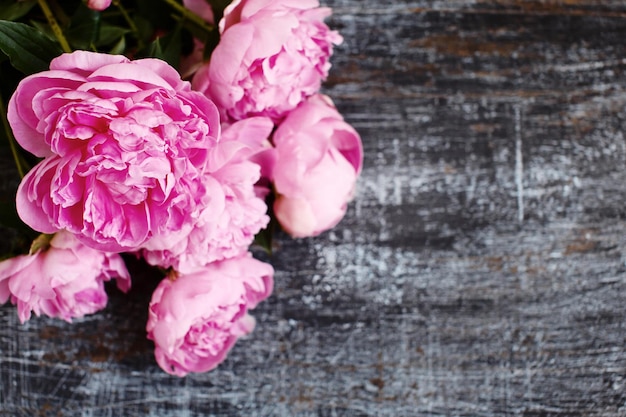 Photo bouquet moelleux de fleurs de pivoine fraîche rose sur un plat en bois sombre minable rayé