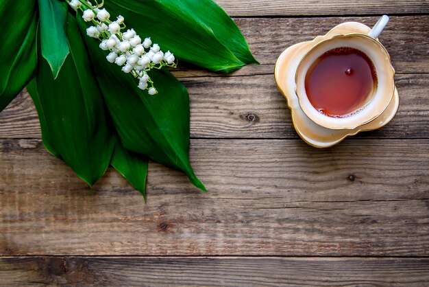 Bouquet de muguet et une tasse de thé sur une table en bois