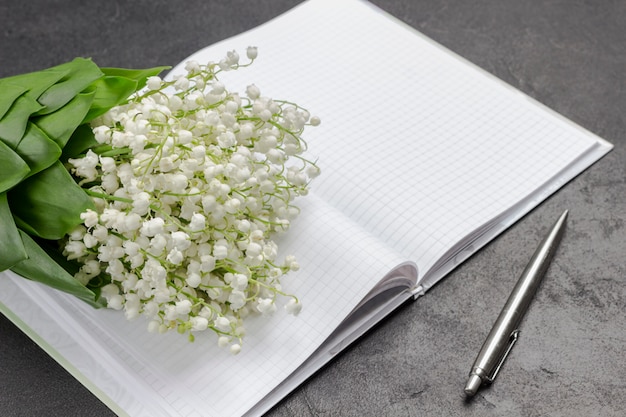 Bouquet de muguets sur une page de cahier ouverte.