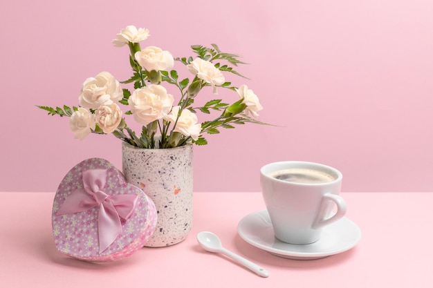 Bouquet d'œillets dans un vase avec une boîte à cadeaux et une tasse de café